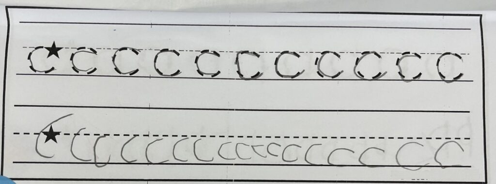 A kindergarten student's handwriting worksheet with two rows. The top row shows the letter c traced over dotted outlines, each one accurate and correctly sized between the lines. The bottom row shows the student's own attempts at the letter c: the letters are small, uneven, drifting away from the baseline, and several are made with more than one stroke.